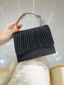 Detail of black pleated evening clutch with silver rhinestone flower ring handle