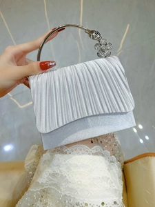 Detailed shot of silver evening bag with pleated fabric and rhinestone flower handle