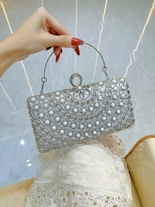 Detail view of silver evening clutch featuring pearl embellishments and crystal clasp