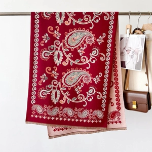 Gros plan sur châle jacquard cachemire rouge avec détails de glands et tricot
