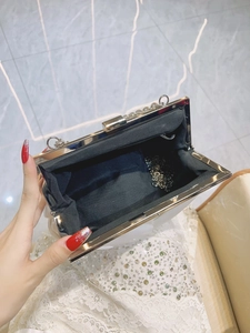 White hard shell evening clutch bag with chain strap and interior view from 45 degree angle