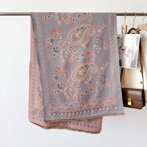 Détail d'un châle à motif cachemire en tricot réversible bleu et rose avec franges