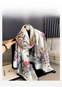 Detail view of floral print silk scarf with golden chain patterns and black border