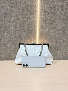 Detail of white pleated clutch bag with silver chain strap beside a phone for scale