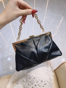Detail of black pleated evening clutch with gold metal frame and detachable chain handle
