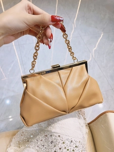 Detail view of light brown ruched clutch bag with chunky gold chain and metal frame