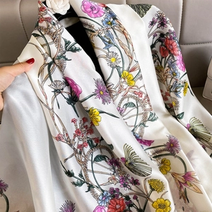 Macro detail of a white floral silk scarf with colorful daisy prints and pearly luster