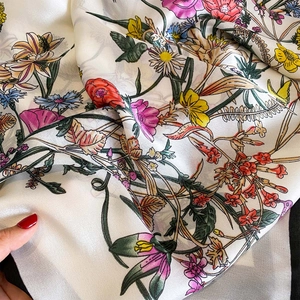 Detailed close-up of floral print silk scarf featuring elegant hand-painted patterns
