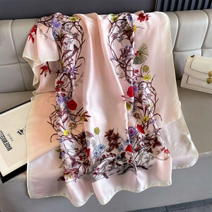 Detail of floral printed silk scarf with rolled edges on a leather surface