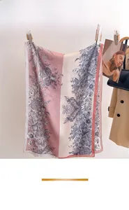 Détail d'un foulard en soie à imprimé floral assorti à un trench-coat beige et un sac