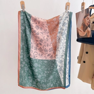 Summer silk scarf with floral print and color block design hanging on a white wall