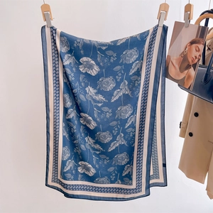 Navy blue silk scarf with floral pattern and white border hung in a French fashion scene