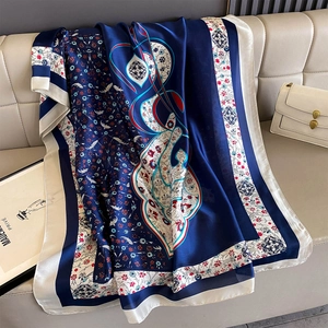 Detailed close-up of navy blue floral paisley silk scarf on white leather surface