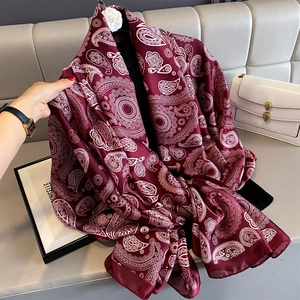 Detail of burgundy paisley print shawl with silky texture and intricate white patterns