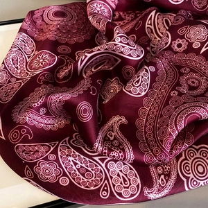 Detailed view of paisley and mandala patterns on wine red silk texture scarf