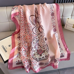 Detailed view of floral pink satin scarf with paisley patterns on grey sofa