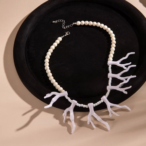 Gros plan sur des breloques corail en acrylique et perles de marbre sur collier bohème