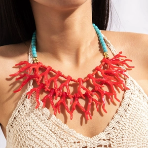 Détail du collier bohème en corail rouge avec perles turquoise sur un modèle de plage