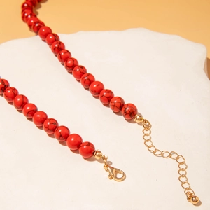 Détail de perles marbrées rouges et fermoir mousqueton doré pour collier corail