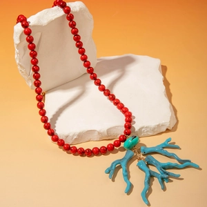 Détail du collier de perles rouges avec pendentif corail turquoise sur pierre