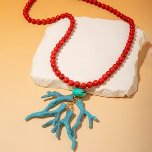 Détail du collier bohème avec perles rouges et pendentifs corail bleu sur socle