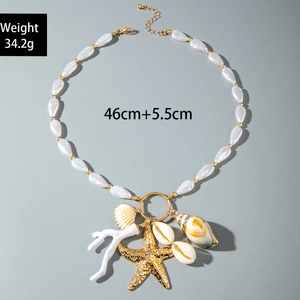 Detail of bohemian shell necklace featuring gold starfish, pearls and coral charms