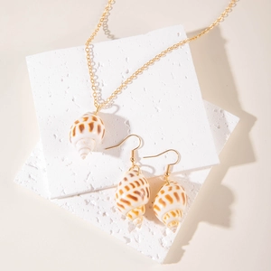 Golden sea shell pendant necklace and earrings set on white display blocks