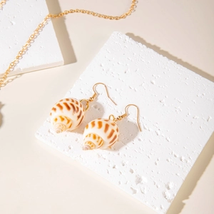 Macro shot of natural shell drop earrings with gold hooks on stone display