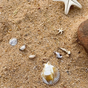 Detail of bohemian gold paperclip necklace with natural shell and starfish charms