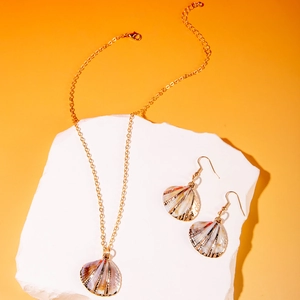 Detail view of natural shell pendant necklace and earrings with gold trim on white stones