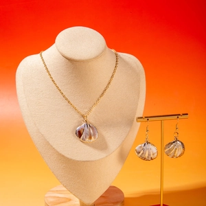 Detail view of golden shell pendant necklace and earrings set on display stand