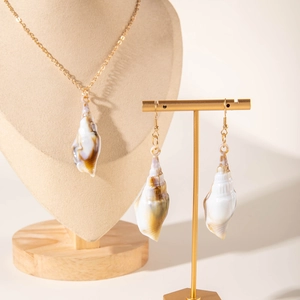 Detail view of natural shell pendant necklace and gold hook earrings on display