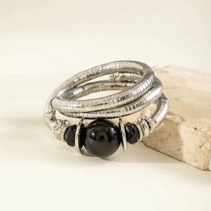 Retro multi-layer snake coil bracelet with black beads on travertine stone display