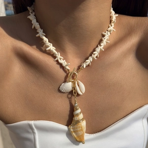 Detail of seashell and starfish pendant necklace with gold accents worn by a model