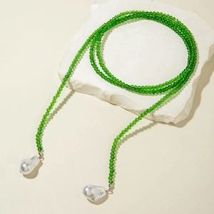 Detail of green crystal bead chain featuring two white baroque pearls on a stone base