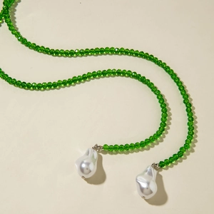 Detail of emerald green crystal beaded necklace with large white baroque pearls