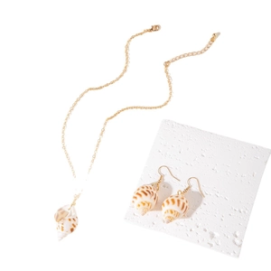 Golden sea shell pendant necklace and earrings set on white stone for beach vacation