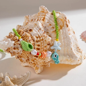 Detail of beaded ocean necklace with starfish and shell charms on a natural seashell