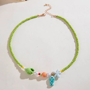Detail of green beaded necklace with starfish, shell and fish pendants for summer beach style