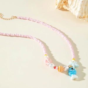 Detail of beaded necklace with starfish pendants and pink shell charms on cream surface