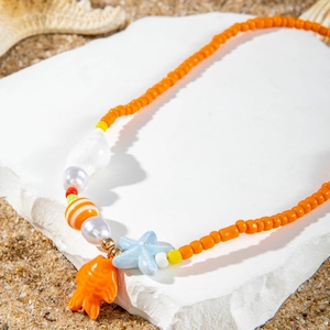 Detail of beach style beaded necklace with starfish, orange fish and shell charms