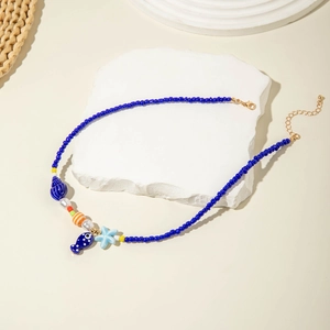Detail of blue beaded necklace with starfish and shell charms on white stone base