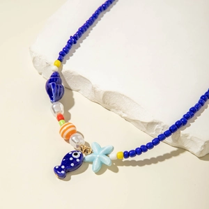 Detail of colorful beaded necklace featuring sea star, shell and blue fish charms
