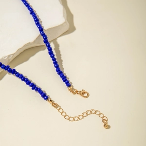 Detailed macro view of cobalt blue beaded necklace with golden lobster clasp and chain