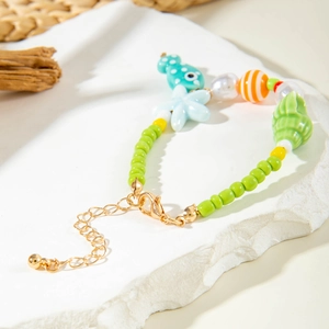 Detail of beaded beach necklace with shell, starfish and fish charms on stone background