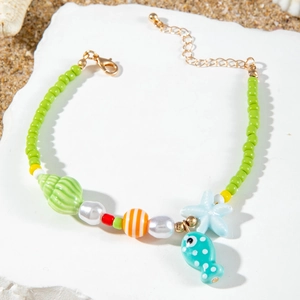 Close-up of ocean-style beaded necklace with starfish and fish pendants on a beach stone
