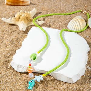 Macro detail of ocean-style beaded necklace with shell and starfish on sandy beach background