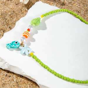 Detail of handmade beaded ocean necklace with green beads, starfish, and fish pendants