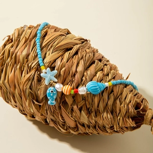 Close-up of ocean-themed beaded necklace with starfish, shell pendants on straw shell prop