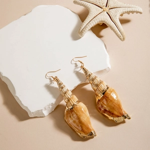 Detail of seashell earrings with gold edges on a stone plate with a starfish
